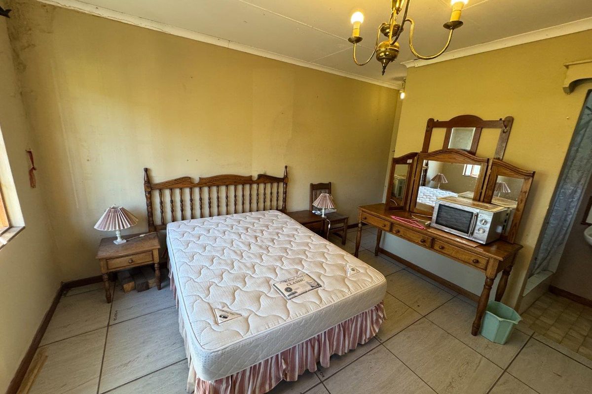 A bedroom featuring tiled flooring and a classic chandelier, requiring cosmetic updates to improve the overall aesthetic and condition of the space.