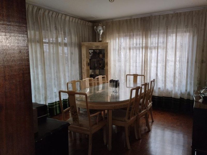 A traditional dining room featuring parquet flooring and large windows with floor-to-ceiling curtains, offering a classic and functional space for formal meals.