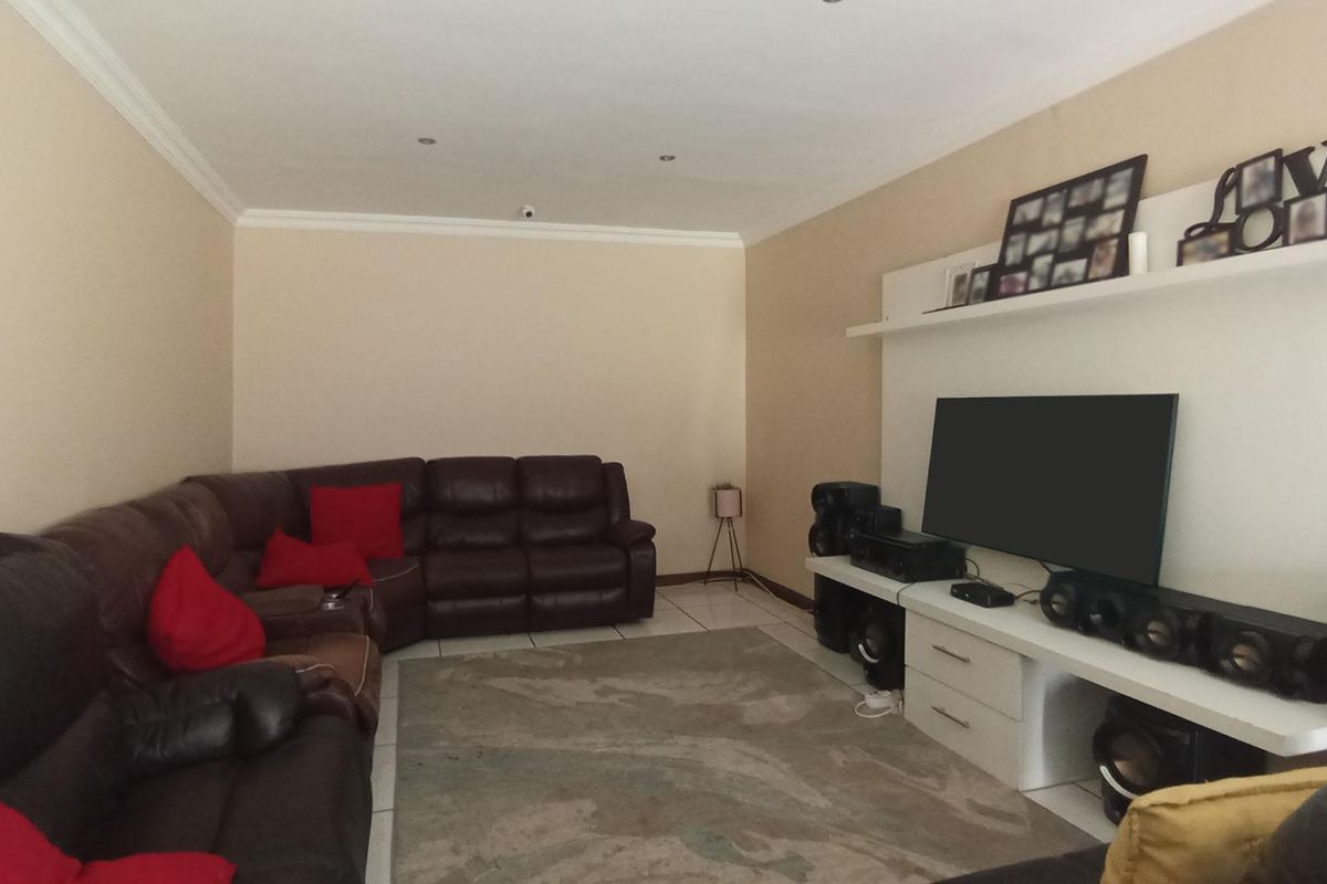 A comfortable living room featuring tiled flooring, recessed ceiling lighting, and a built-in media console unit.