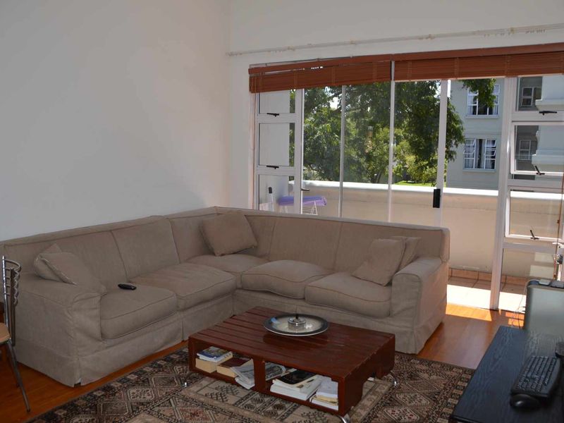 A living room featuring timber flooring and large sliding glass doors that provide access to an outdoor balcony area.