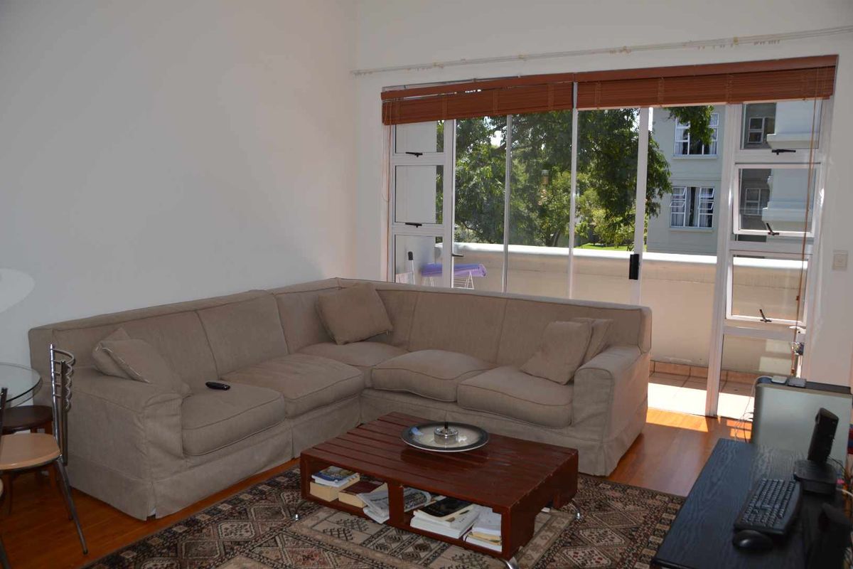 A living room featuring timber flooring and large sliding glass doors that provide access to an outdoor balcony area.