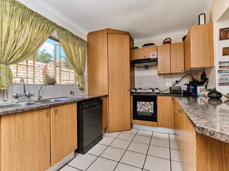 Functional kitchen featuring laminate cabinetry, granite countertops, built-in oven with gas hob, extractor fan, and tiled flooring.