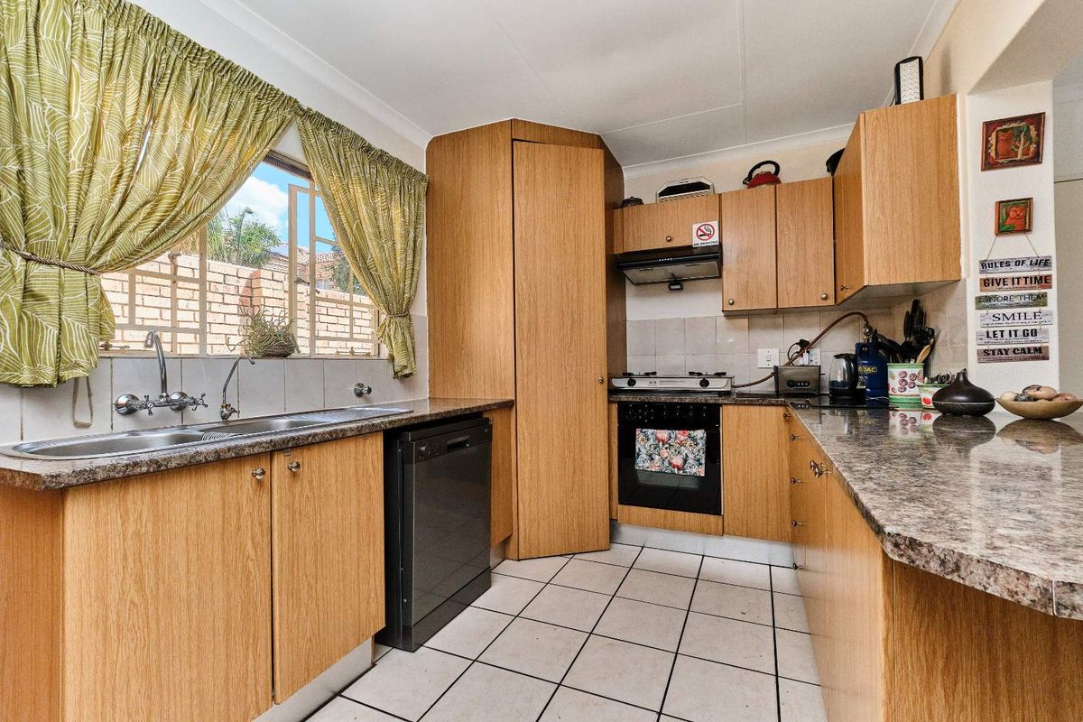 Functional kitchen featuring laminate cabinetry, granite countertops, built-in oven with gas hob, extractor fan, and tiled flooring.