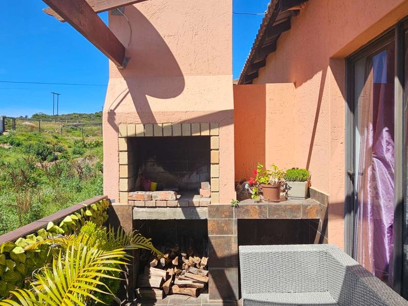 Outdoor patio area featuring a built-in brick braai, tiled prep surface, and timber pergola, providing a functional space for outdoor entertaining.