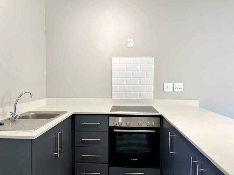 Modern kitchen featuring dark grey cabinetry, white quartz countertops, a built-in Bosch oven, electric hob, and a clean subway tile splashback.