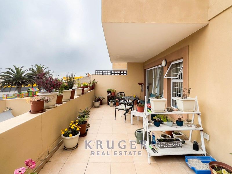 A spacious covered balcony featuring tiled flooring and a sliding glass door, offering an outdoor area suitable for relaxation.