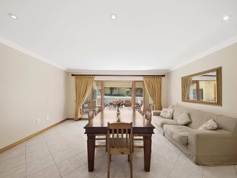 A bright dining room featuring tiled flooring, recessed downlighting, and large sliding glass doors that provide direct access to the outdoor patio area.