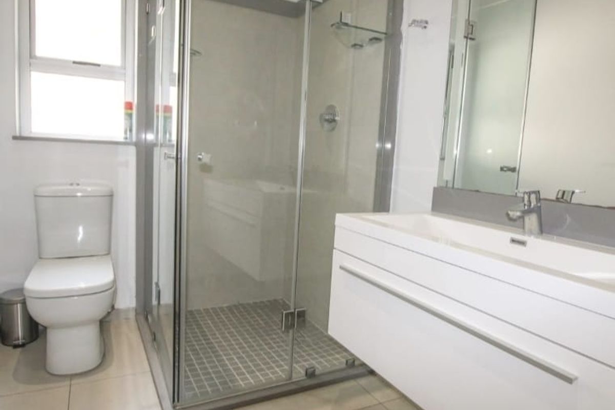 Modern bathroom featuring a floating vanity, glass-enclosed shower, and a white ceramic toilet.