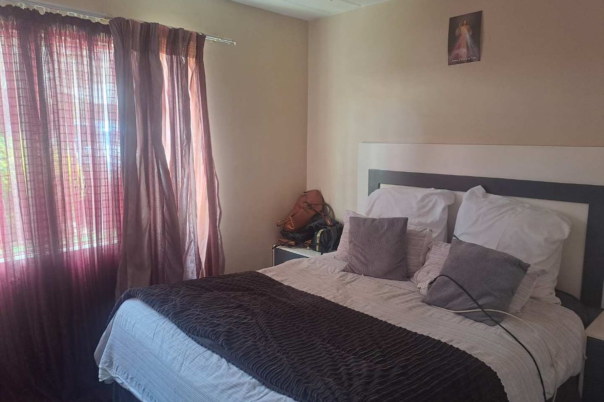A standard bedroom featuring a built-in headboard and tiled flooring, providing a functional sleeping space.
