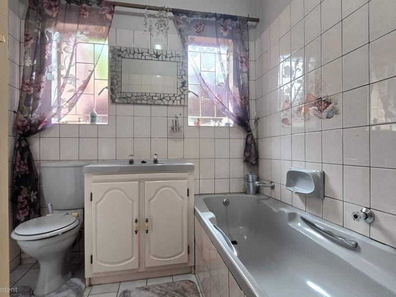 A functional bathroom featuring a built-in vanity, bathtub, and toilet, finished with classic ceramic wall and floor tiles.