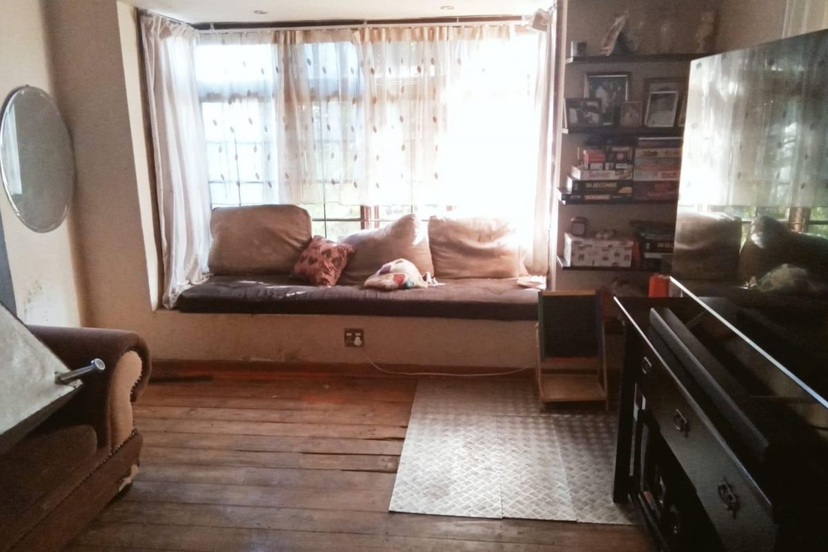 A living room featuring a large bay window with a built-in window seat and original timber flooring.