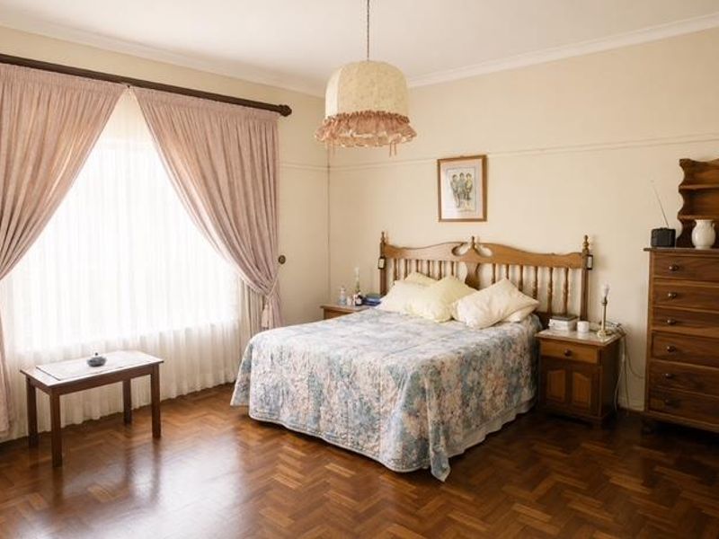 A spacious bedroom featuring classic parquet flooring, coved cornicing, and a picture rail, offering a traditional and well-maintained living space.