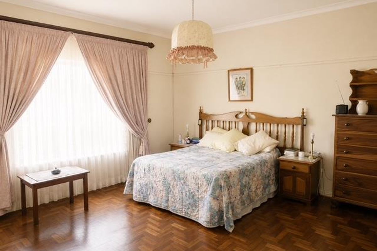 A spacious bedroom featuring classic parquet flooring, coved cornicing, and a picture rail, offering a traditional and well-maintained living space.