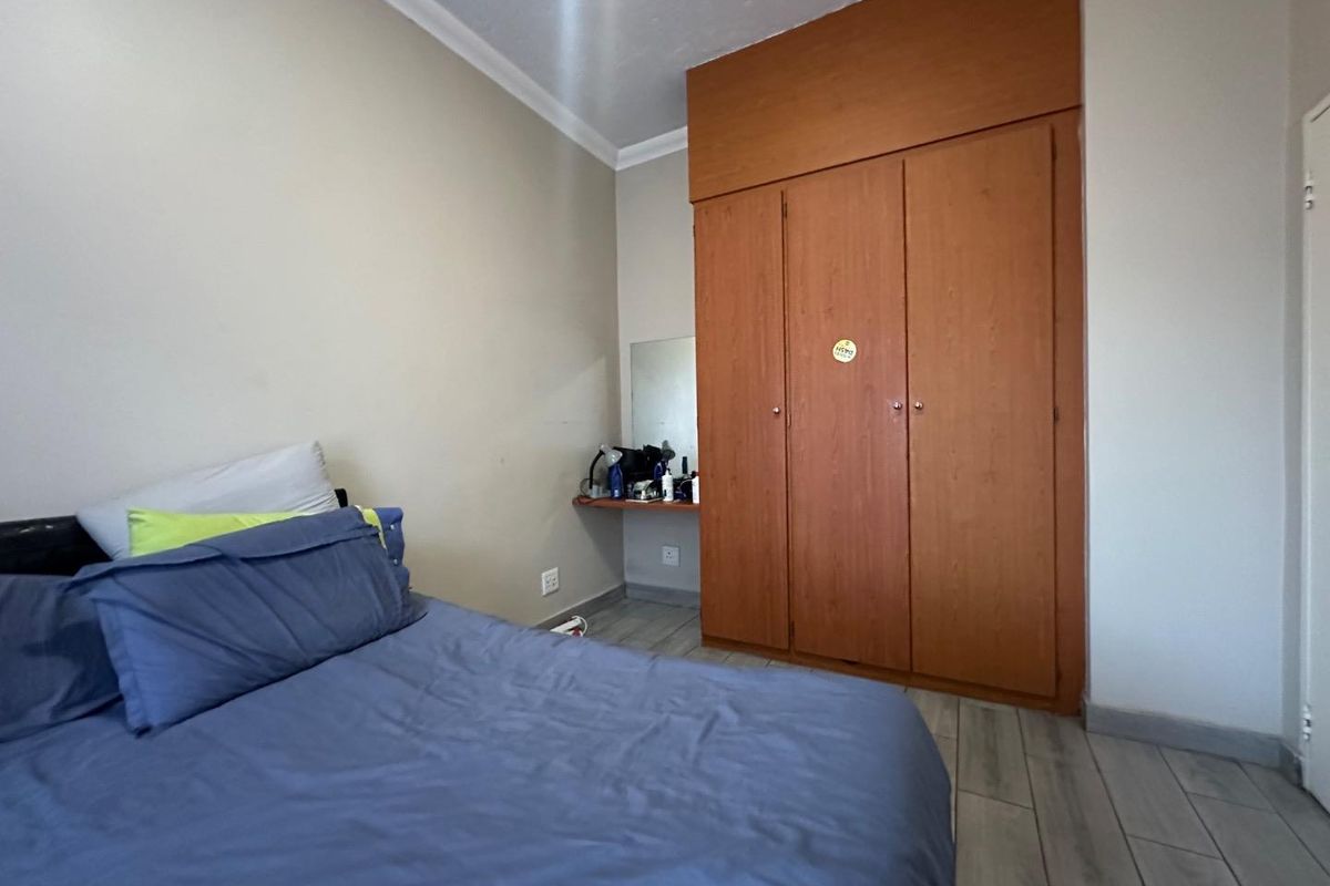 A bedroom featuring built-in wooden cupboards with integrated shelving and tiled flooring.