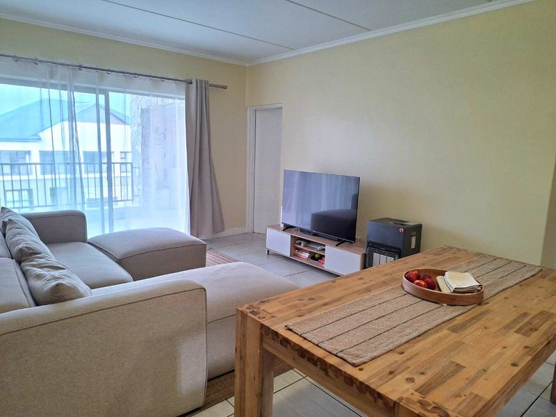 Open plan living area featuring tiled flooring and a large sliding glass door providing access to the balcony.