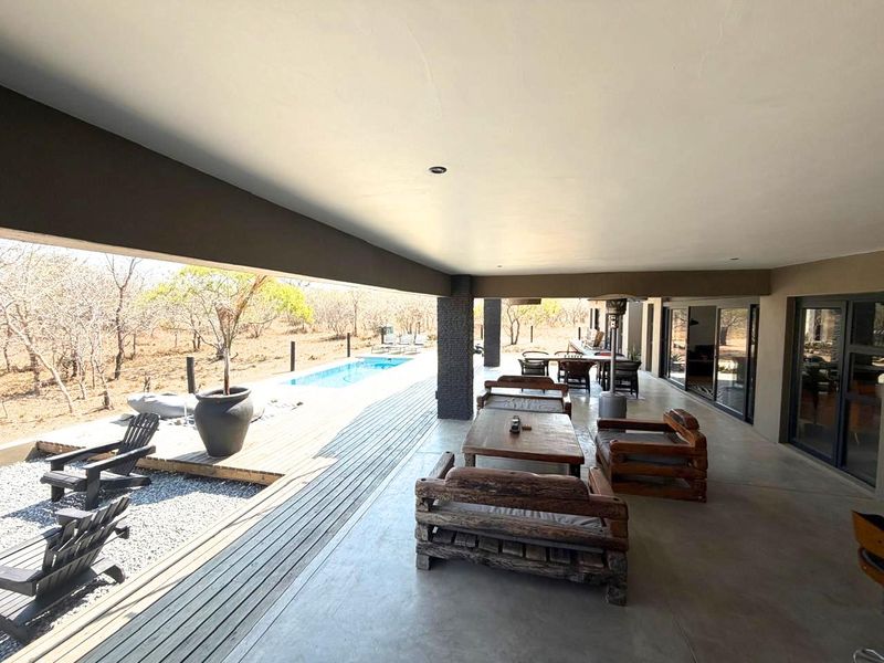 Spacious covered patio featuring concrete flooring, recessed lighting, and seamless access to the outdoor timber deck and swimming pool area.