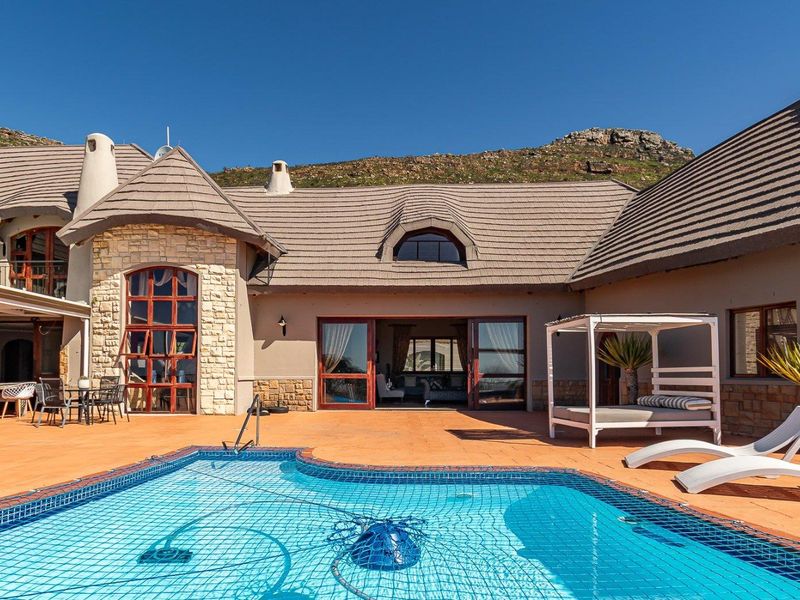 Spacious outdoor pool area featuring a tiled patio, stone-clad architectural details, and direct access to the main residence through large sliding doors.