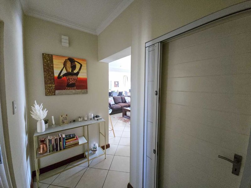 A bright hallway featuring tiled flooring and a folding door, providing a clear transition into the main living area of the home.