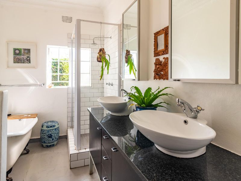 A well-appointed bathroom featuring a double vanity with vessel sinks, a walk-in shower with subway tiling, and a classic freestanding bathtub.