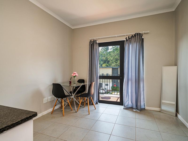 Open plan living area featuring tiled flooring and direct access to a private balcony through a glass door.