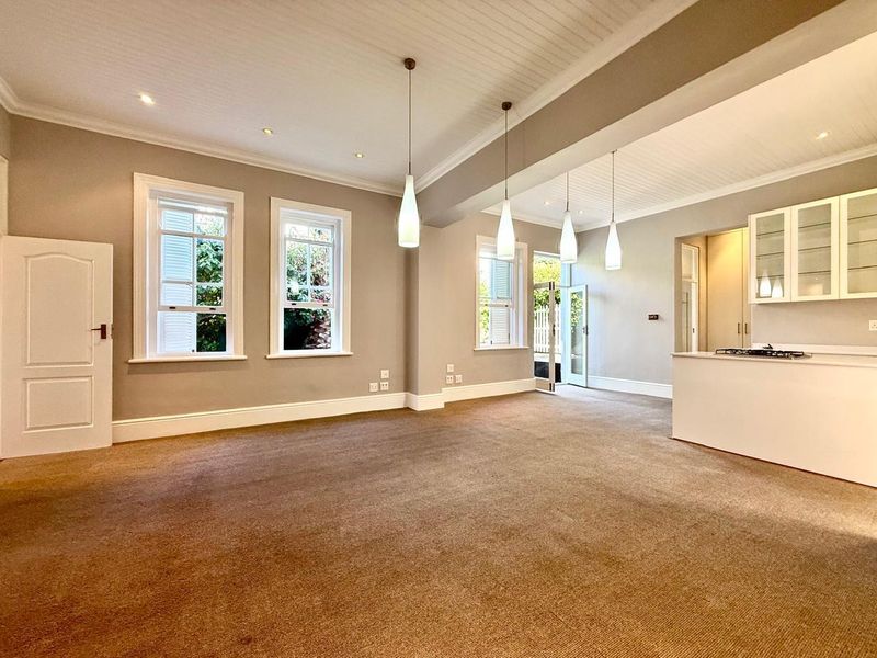 Spacious open-plan living and kitchen area featuring beadboard ceilings, pendant lighting, and large sash windows, providing a bright and versatile living space.