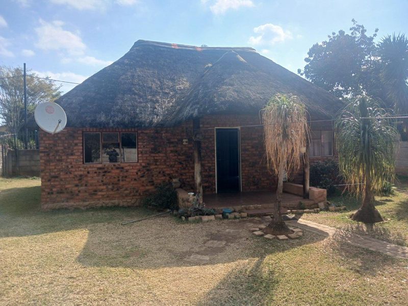 A charming cottage featuring a traditional thatched roof and exposed brick exterior with a covered front porch entrance.