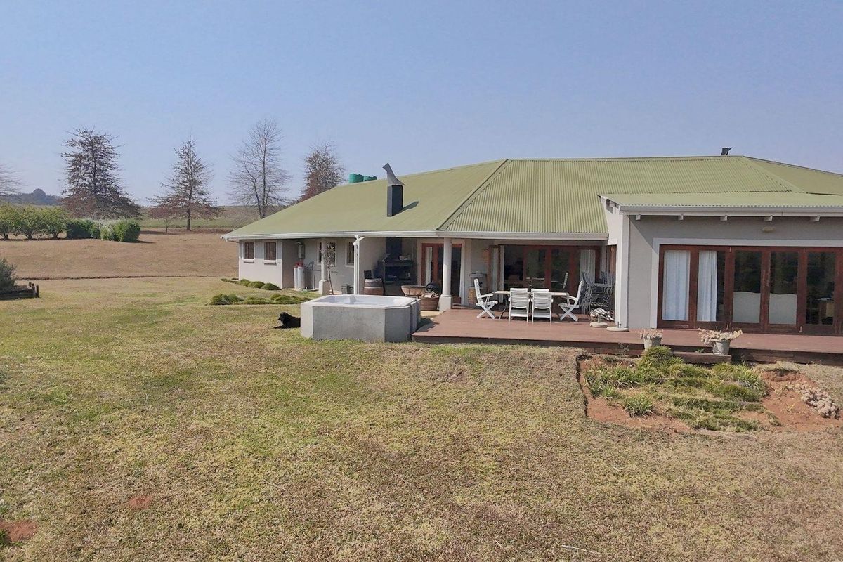 Rear view of the commercial property featuring a covered wooden deck, built-in outdoor braai, and a small plunge pool set in a spacious garden.