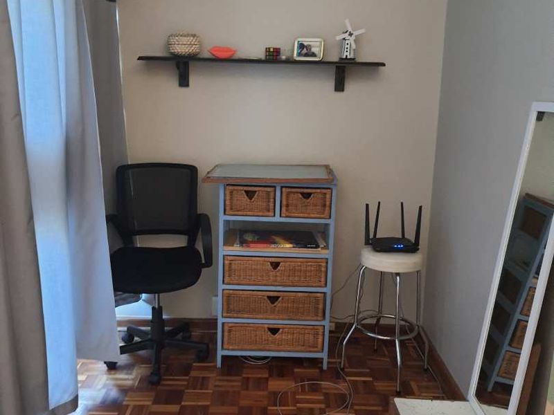 A compact bedroom featuring classic parquet flooring and a mounted wall shelf, offering a functional space with potential for modern updates.
