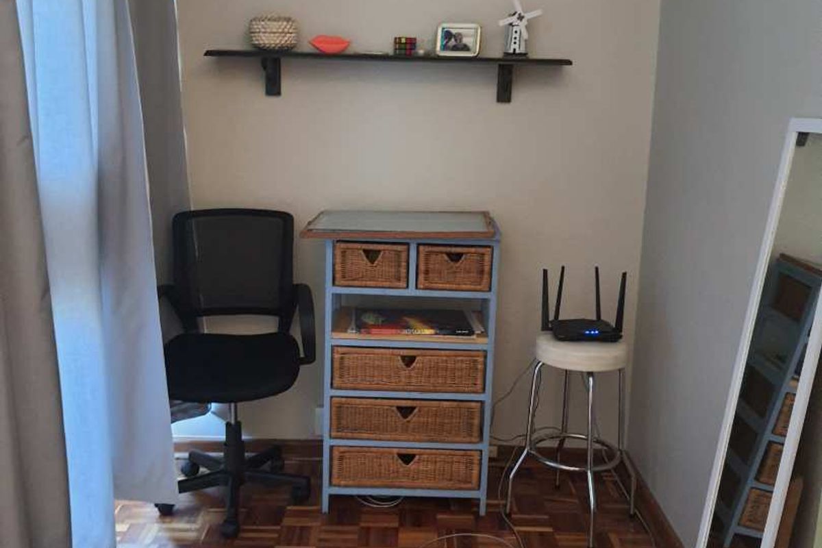 A compact bedroom featuring classic parquet flooring and a mounted wall shelf, offering a functional space with potential for modern updates.