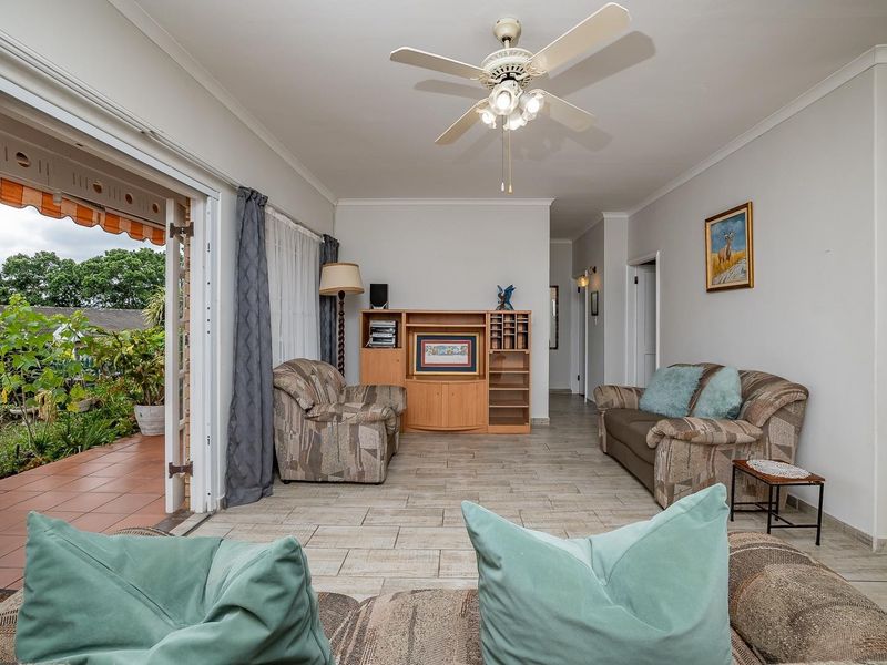 Spacious living room featuring tiled flooring, a ceiling fan, and large sliding glass doors providing direct access to the outdoor patio area.