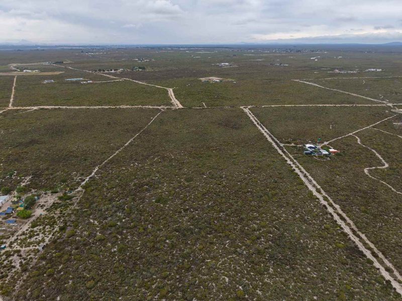 An aerial view of a large expanse of vacant agricultural land featuring natural vegetation and dirt access tracks.