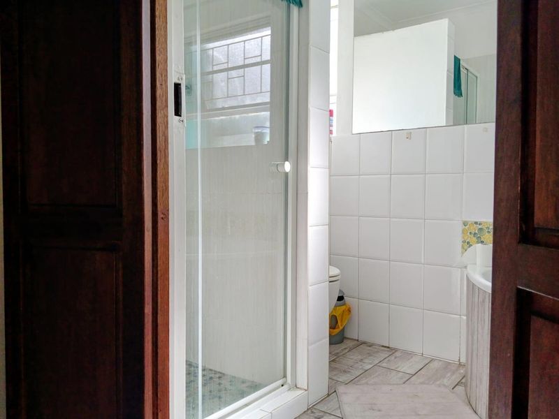 A functional bathroom featuring a glass-enclosed shower, tiled walls, and neutral flooring, offering a clean canvas for potential modern updates.