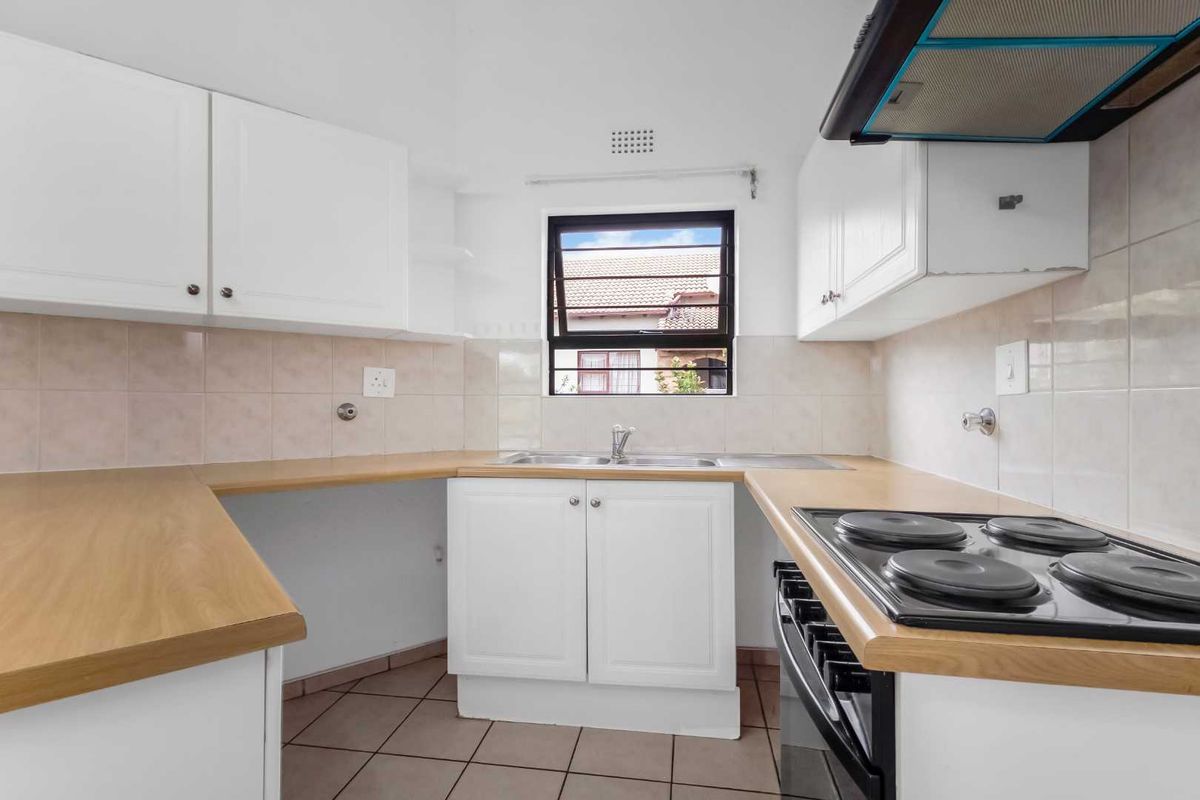 Functional kitchen featuring white cabinetry, laminate countertops, a built-in electric stove with extractor fan, and tiled flooring.