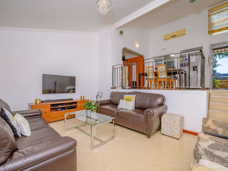 Open-plan living area featuring tiled floors, a raised dining section with metal balustrade, and split-system air conditioning.