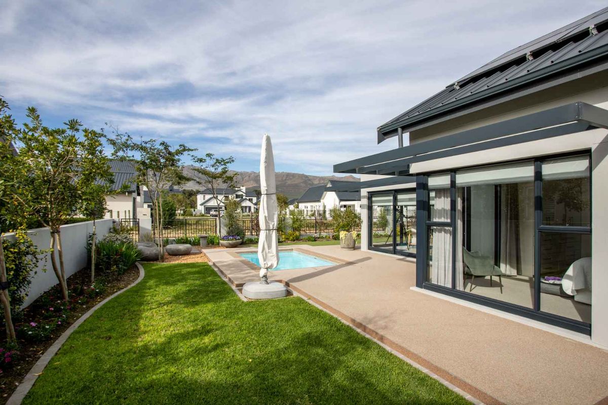 A well-maintained rear garden featuring a small swimming pool, a paved patio area, and modern sliding glass doors leading into the home.