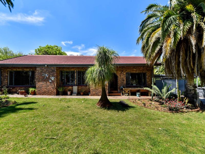 A well-maintained single-story face brick house featuring a tiled roof, paved walkway, and established garden area.