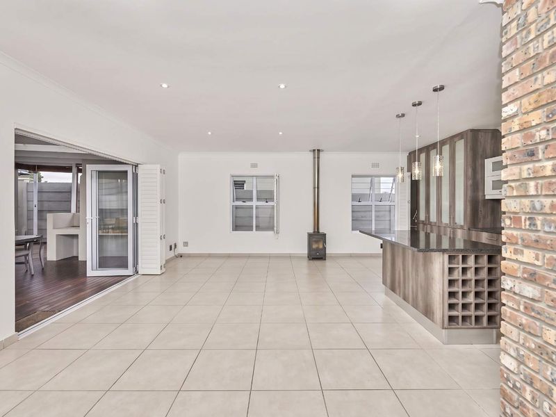 Spacious open-plan living and kitchen area featuring tiled floors, a modern kitchen island with granite tops, a fireplace, and seamless access to the patio.
