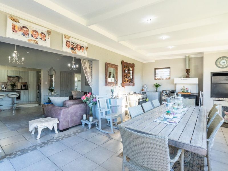 Spacious open-plan living and dining area featuring tiled floors, recessed lighting, and a built-in fireplace, seamlessly connected to a functional kitchen space.