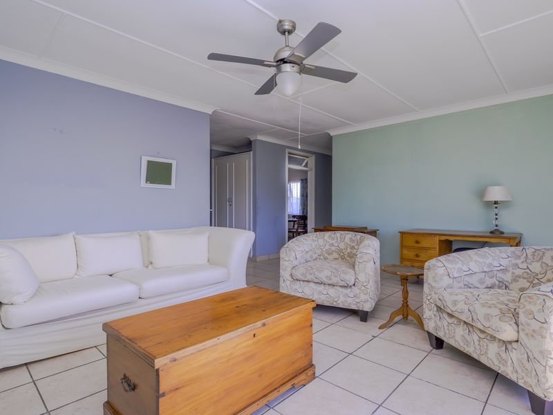 A spacious living room featuring tiled flooring, a ceiling fan, and neutral wall tones, providing a comfortable and functional area for relaxation.