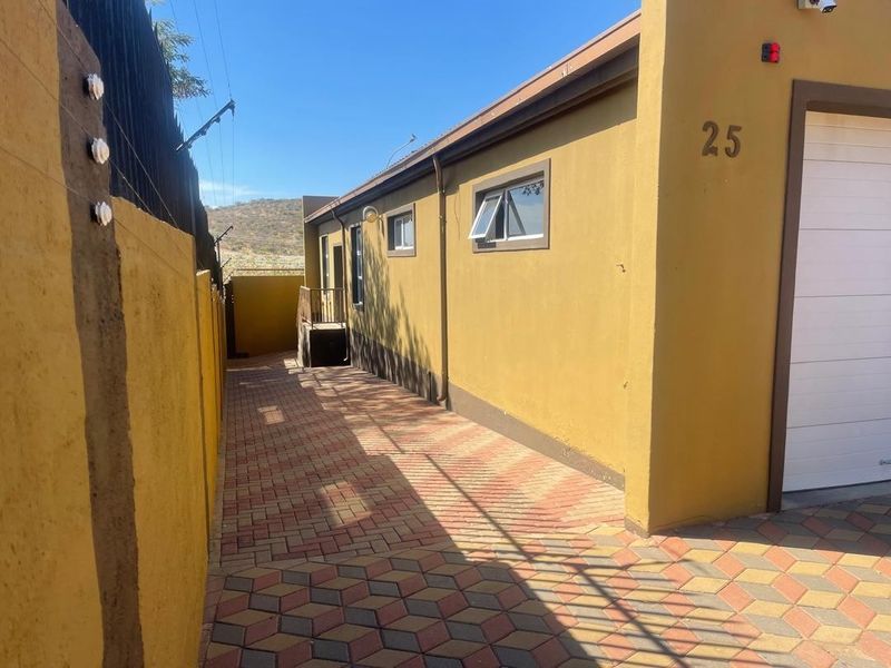 Side view of the property featuring a paved driveway, secure electric fencing, and access to the garage.
