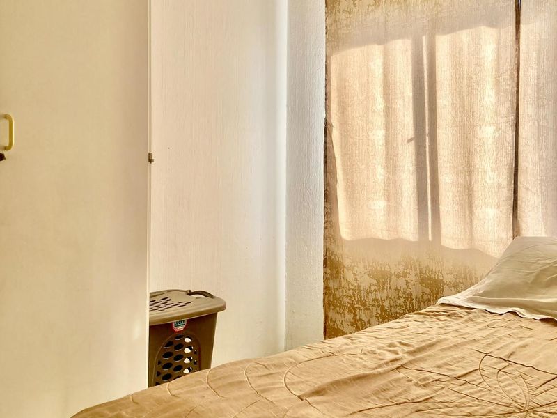 A bedroom featuring a built-in cupboard and natural light filtering through window curtains.