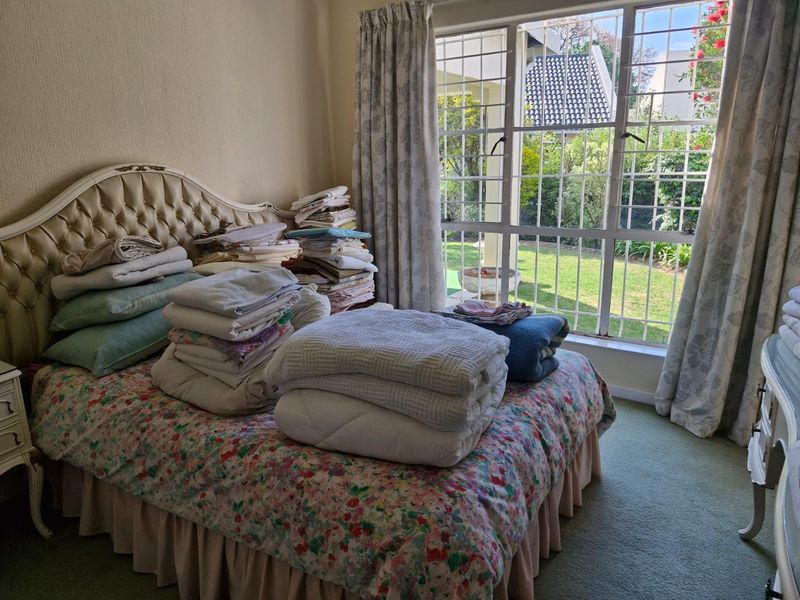 A bedroom featuring large windows with security bars, providing natural light and views of the garden area.