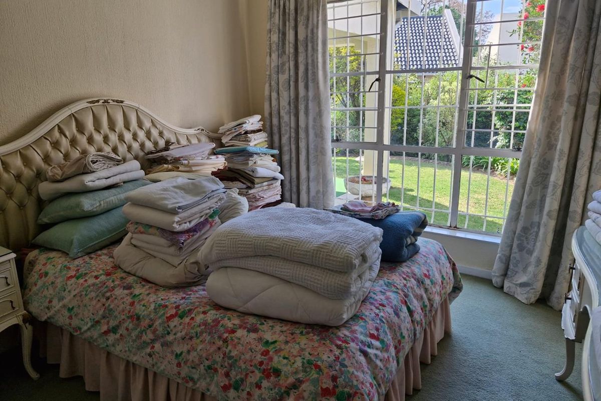 A bedroom featuring large windows with security bars, providing natural light and views of the garden area.
