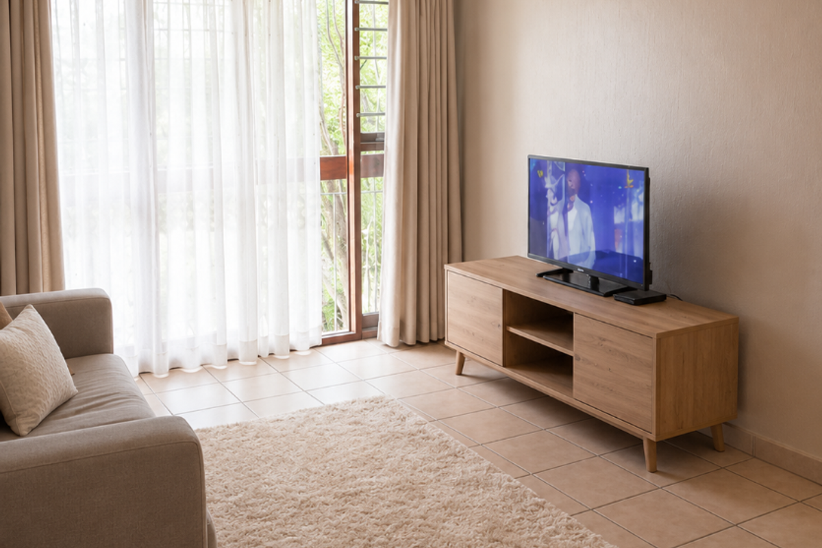 A bright living room featuring neutral tiled flooring, coving, and a large sliding glass door providing access to the exterior.
