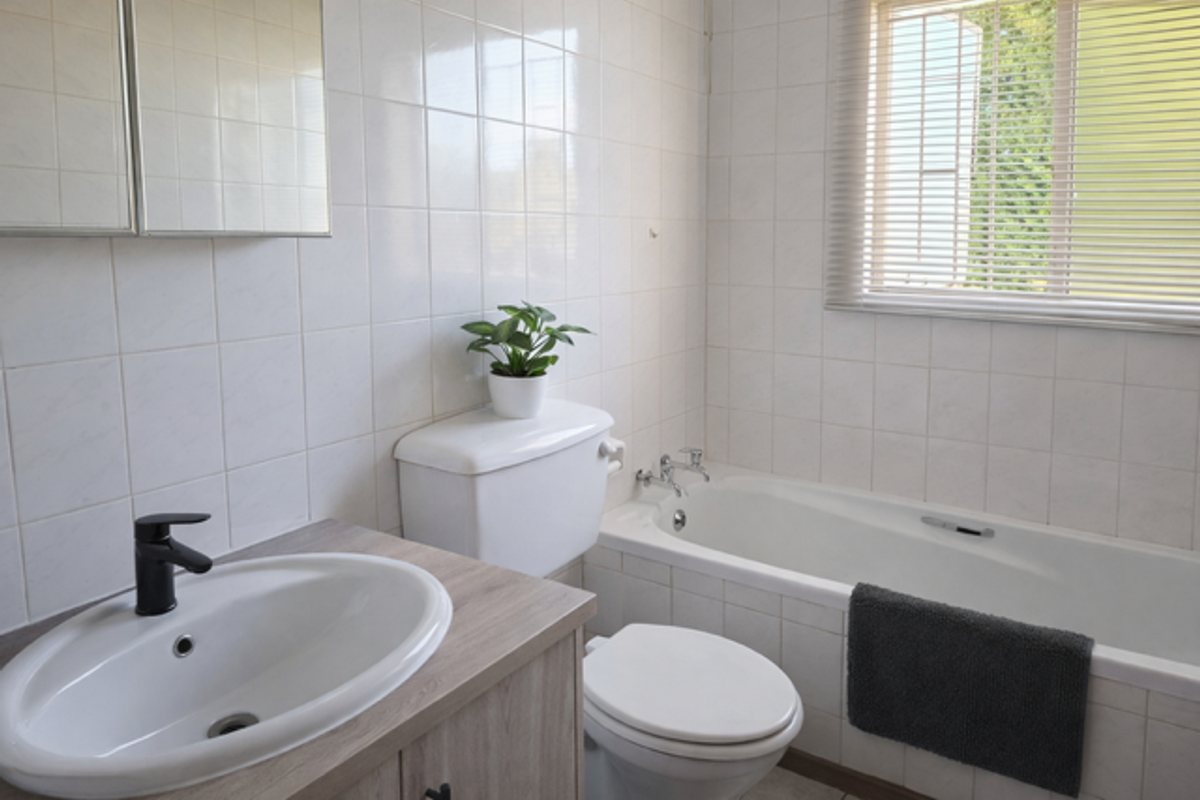 A functional bathroom featuring a built-in bathtub, a vanity with a modern basin, and tiled walls with a window for natural light.