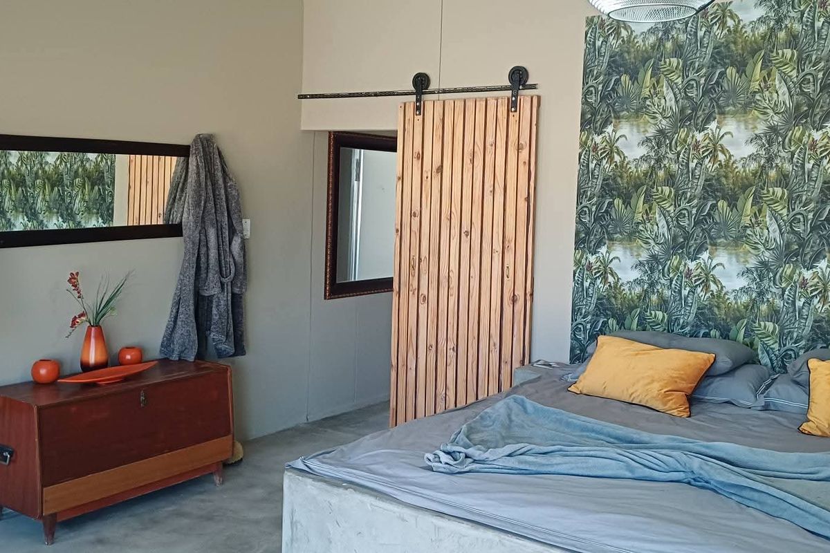 A bedroom featuring a sliding wooden barn door, concrete bed base, and wall-mounted air conditioning unit.