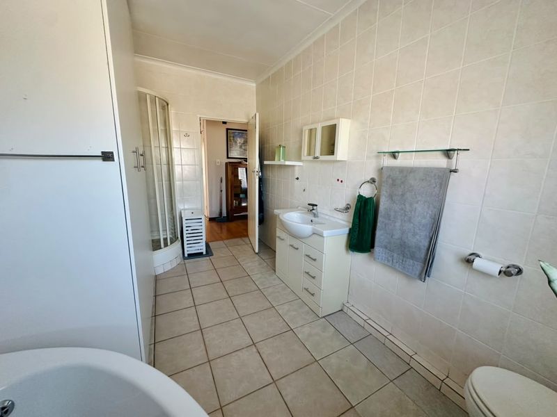 A functional bathroom featuring a shower enclosure, vanity cabinet with basin, and tiled walls and flooring. The space offers a practical layout.