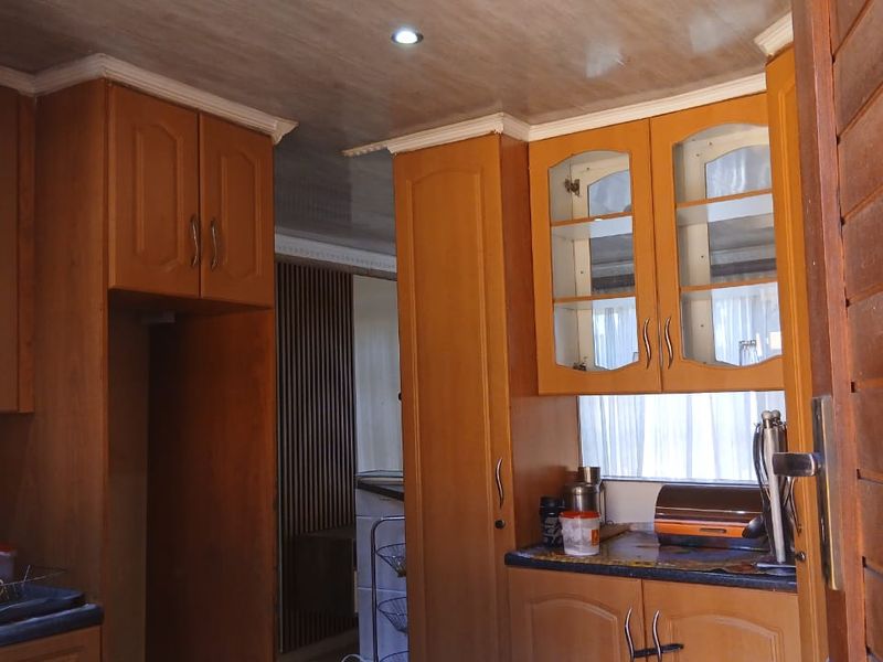A functional kitchen featuring traditional wooden cabinetry, laminate countertops, and recessed ceiling lighting, offering a classic layout with potential for modern updates.