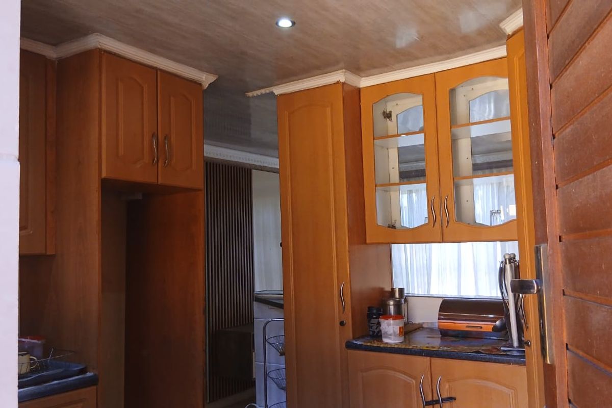 A functional kitchen featuring traditional wooden cabinetry, laminate countertops, and recessed ceiling lighting, offering a classic layout with potential for modern updates.