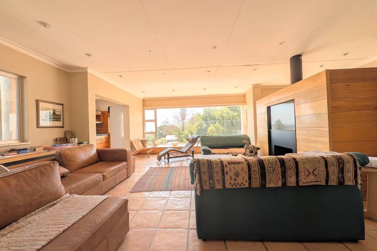 Spacious living room featuring terracotta tiled flooring, a striking timber-clad feature wall with a built-in fireplace, and large windows offering natural light.